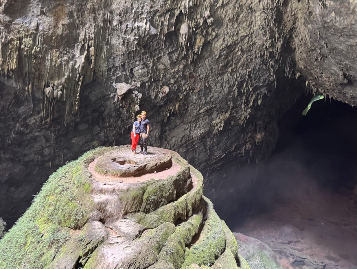 Thomas and Victoria standing together atop a rock formation deep inside a cave.
