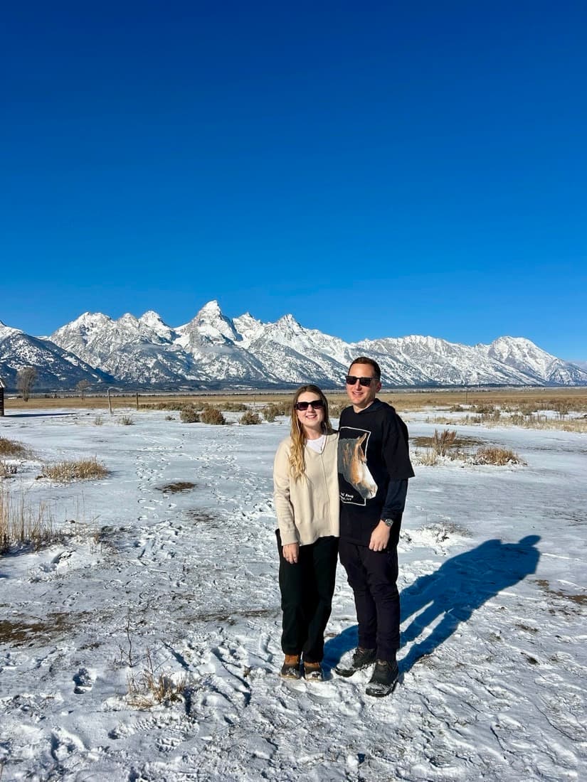 Thomas and Victoria standing together in front of the snow-covered Teton mountains.